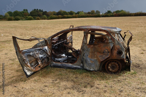 Burnt out wreak of a car dumped in middle of field during summer Heat wave 