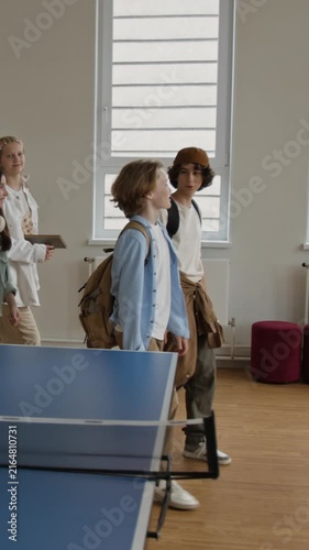 Vertical shot of teenagers with backpacks walking through school hallway, talking and smiling. Footage is perfect for school enrollment campaigns