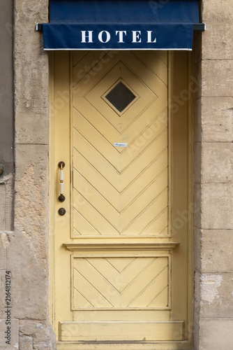 Vintage yellow hotel door with blue awning and diamond window