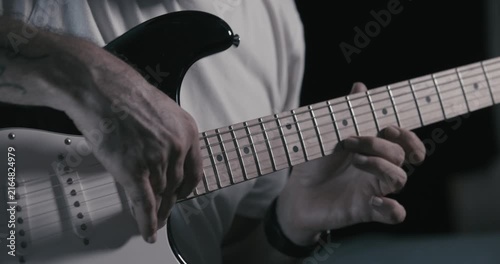 Guitarist's hands playing riff on electric guitar, close-up