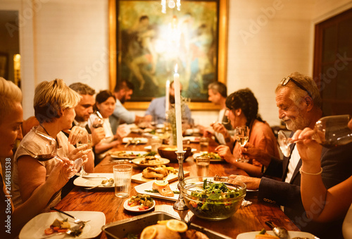 Принти на полотні Warm family dinner gathering around a candlelit table
