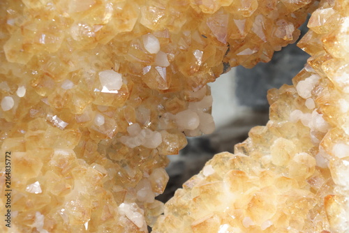 A close-up of a yellow geode of citrine. Mineral, crystal and gemstone and geology. Citrine druse and raw stone. Yellow background with minerals and crystal points. Geogical formation.