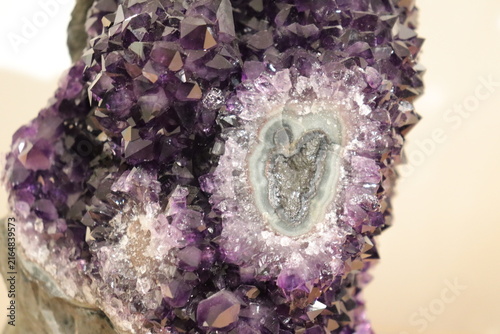 A close-up of a purple geode of amethyst. Mineral, crystal and gemstone and geology. Amethyst druse and raw stone. Purple and violet background with minerals and crystal points. Geogical formation.