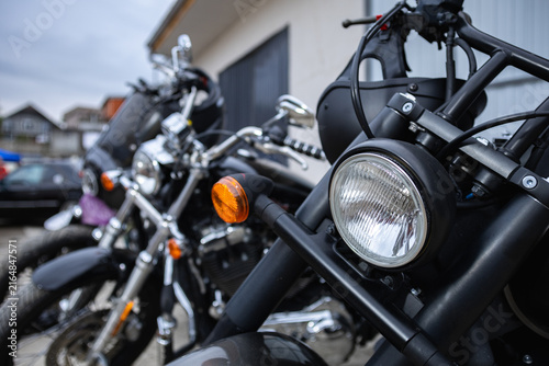 Fotografie Custom motorcycles parked in a row with focus on a matte black headlight