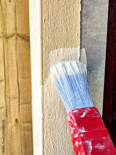 Close up view of ivory coloured masonry paint being brushed onto the edge of a garage door.