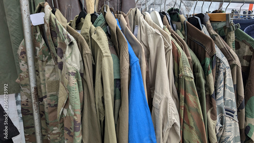 Bild auf Leinwand Military surplus clothing hanging on a rack with camouflage jackets and shirts