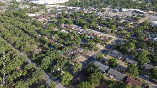 Diagonal roadway junctions link quiet neighborhood properties near Airport Freeway. Mature oak trees, private driveways, single family dwellings demonstrate residential growth, Hurst, Texas