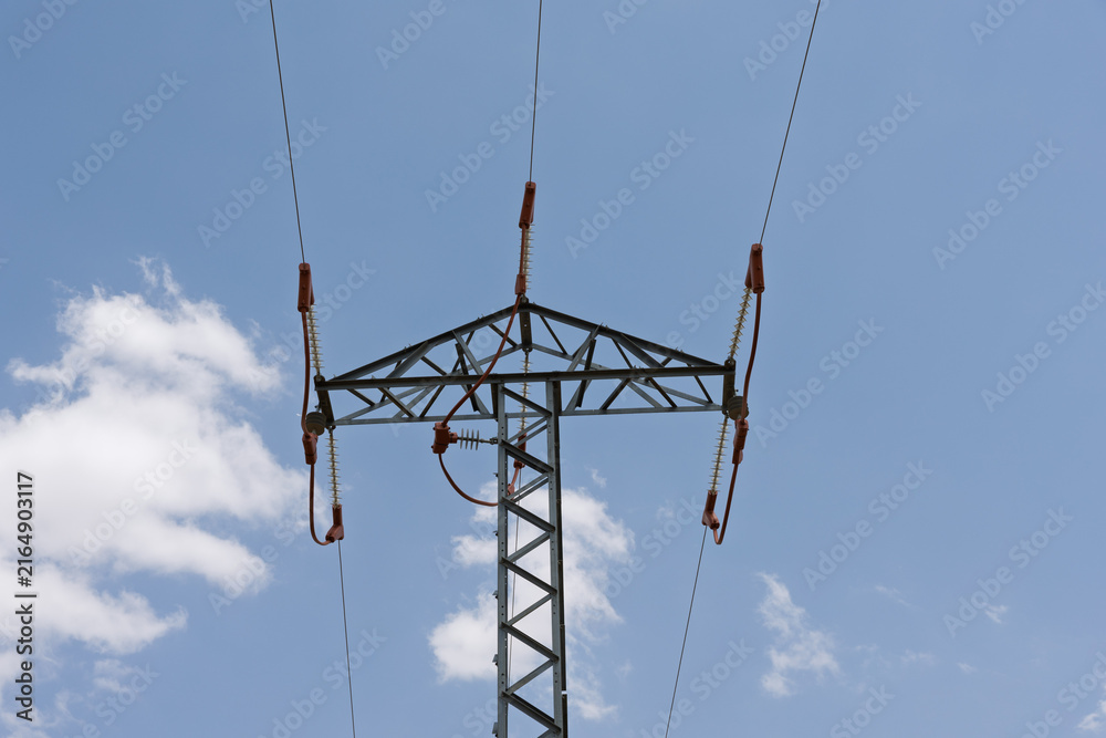 Obraz premium Electricity transmission pylon supporting power lines in blue sky