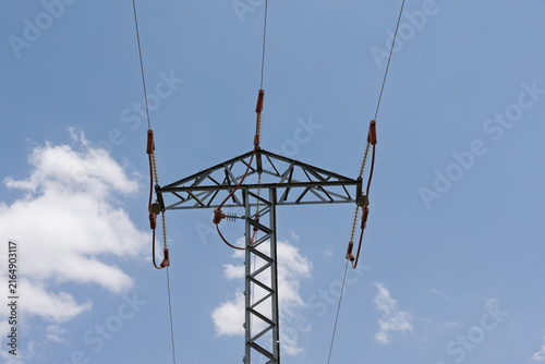 Quadro su tela Electricity transmission pylon supporting power lines in blue sky