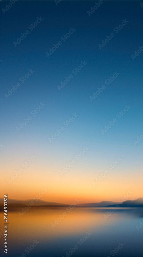 Obraz premium Calm Horizon: A serene landscape photograph captures the tranquil beauty of a clear horizon where a vibrant sunset meets the calm water, reflecting a breathtaking gradient of orange and blue.