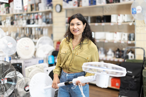 Foto Latino American woman chooses a fan for the summer heat