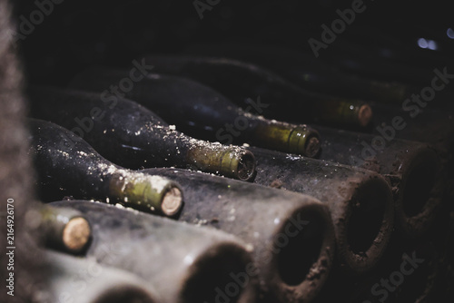 Dust‑covered wine bottles lie in rows inside a Beaune cellar in Burgundy, France, showing years of aging and tradition.