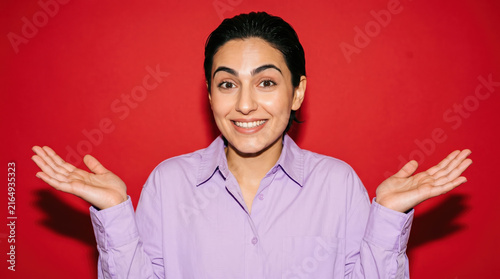 Person shrugging playfully on a red studio backdrop