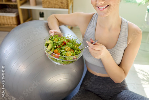 Obraz na płótnie Smiling woman eating salad after home workout
