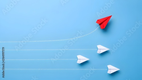Red paper airplane changing direction and leading a group of white planes on blue background, illustrating innovation, business leadership, and new strategy.