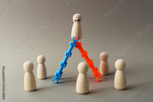 Foto Leader balanced on two ladders surrounded by his team