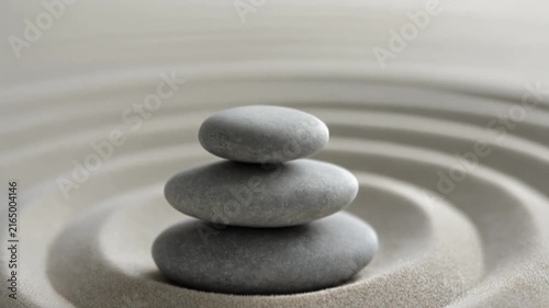 Balanced grey zen stones stacked neatly in raked sand motion video for peaceful meditation practice