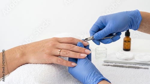 Manicurist using cuticle nippers to trim a clients fingernail during a manicure