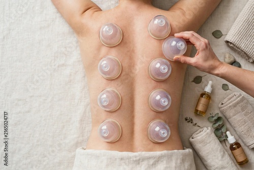 A man is treated with massage therapy using balls on her back, showcasing a method to alleviate muscle tension