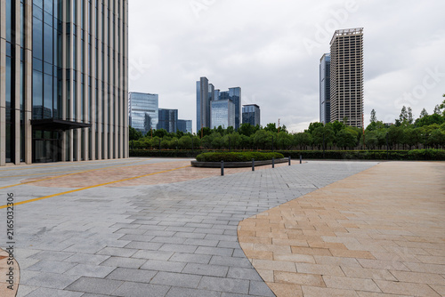 Empty urban plaza with trees and modern skyline