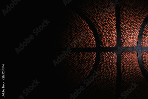 Macro texture of an orange basketball against a black background. Concept of sports competition, athletic training, and championship game.