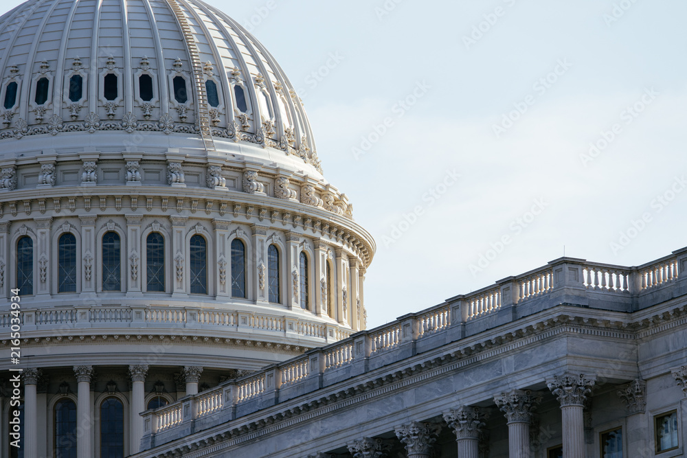 Fototapeta premium United States Capitol building with iconic dome and American flag under clear blue sky in Washington DC, USA. g.