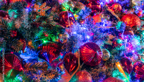 Fotografía Close up of colorful Christmas tree illuminated with glowing LED lights, red baubles, glitter ornaments and evergreen branches creating festive background for holiday and New Year celebrations