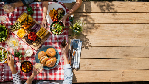 Overhead picnic meal with grilled food, burgers, salads, and drinks outdoors