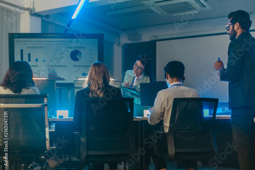 Cybersecurity team monitoring security information and event management dashboard in dark war room