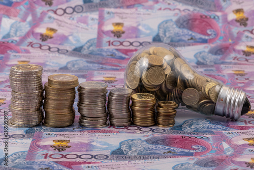 Conceptual story about the cost of electricity in Kazakhstan with an incandescent light bulb filled with coins worth 1 Kazakh tenge