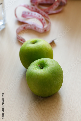 Two fresh green apples with a measuring tape in the background, representing healthy eating, balanced nutrition, weight management, fitness, and wellness lifestyle concepts