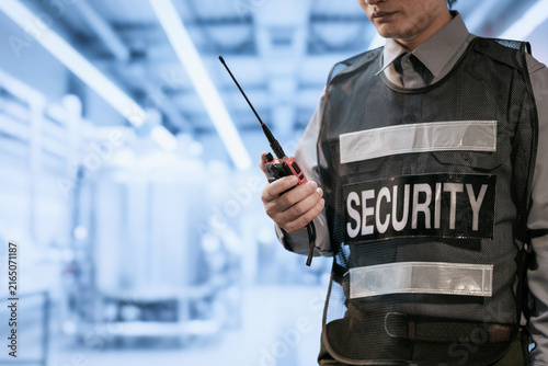 Obraz na płótnie Close view of a uniformed security guard holding a two-way radio in a bright modern building corridor
