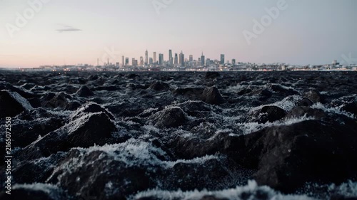 Rugged Rocks in Foreground with Distant City Skyline Across Horizon.