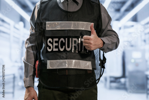 Konstfotografi Close-up of a uniformed security guard wearing a protective vest and giving a thumbs-up in a modern indoor public building