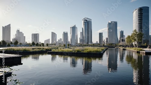 Sunny city skyline by tranquil river reflection.