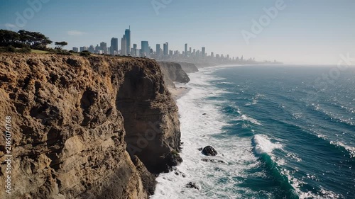 Dramatic Cliffside Coastline With Ocean Waves And Distant City Skyline.