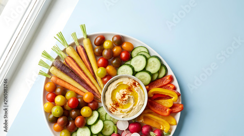 Healthy Fresh Vegetable Crudites Platter with Creamy Hummus Dip Olive Oil and Paprika on Colorful Background