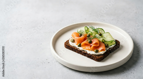 Open-faced smoked salmon sandwich on rye bread with cucumber and dill