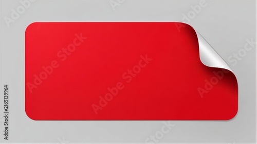 Red rectangular sticker peeling at corner on gray surface