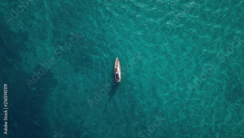 Lone boat navigating through clear turquoise waters on a sunny day showcasing natural tranquility