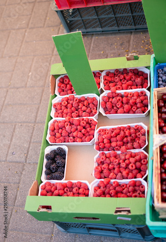 Top view photo of raspberries and blueberries in boxes at a local market.