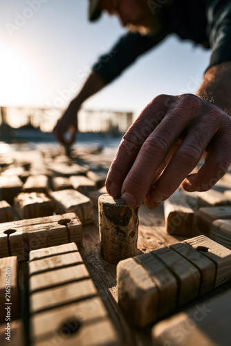 Hands place cork among wooden blocks