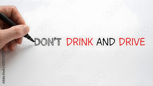 A hand holding a marker writing the words dont drink and drive on a white board