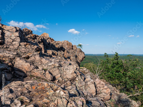 Foto View from the top of Černolické skály in Czechia, with rugged Ordovician quartzite rocks overlooking a vast green forest landscape under a clear blue summer sky