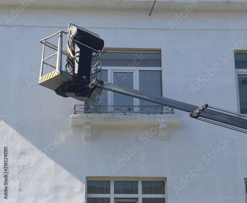 Aerial Boom Lift Worker Performing Building Exterior Maintenance and Painting.

