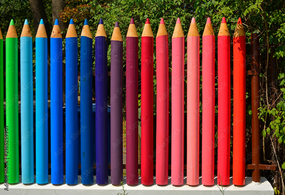 Fototapeta premium kolorowe pasy, tęczowe prążki, kolorowe kredki z drewna, ogrodzenie w formie kolorowych kredek z drewnianych bali, rainbow stripes, fence made of wooden logs shaped like colorful crayons