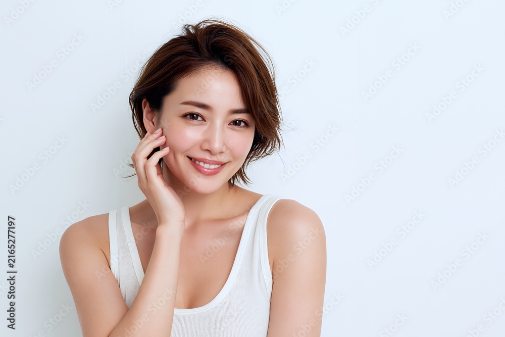 Naklejka premium 白背景で微笑む美しい日本人女性の輝く素肌と明るい笑顔