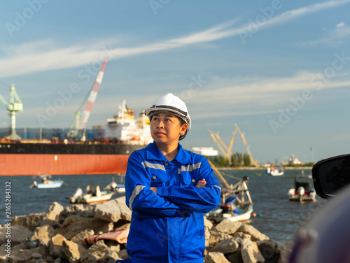 Professional engineer in uniform and hard hat standing confidently at industrial port