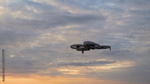 Drone flying over a sandy beach by the sea at sunset, capturing a beautiful coastal landscape from above. Warm golden evening light, calm sea, sandy shoreline, and colorful sunset