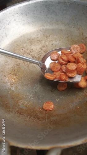 Cooking Thai Chinese sausage fried rice (Khao Phad Gun Chiang). Frying sliced sausage, scrambling eggs, tossing cooked rice, onions, carrots, seasoning sauce, and spring onions.